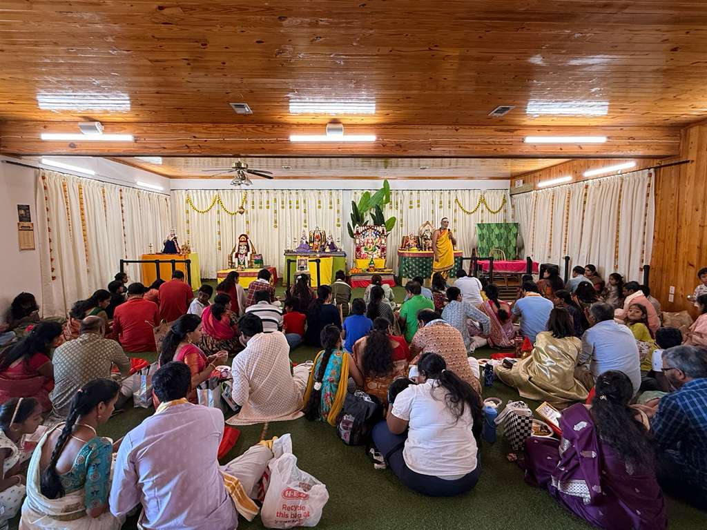 Close-up of a decorated Kalasha with coconuts, mango leaves, and flowers used in the Sathya Narayana Swamy Vratham.